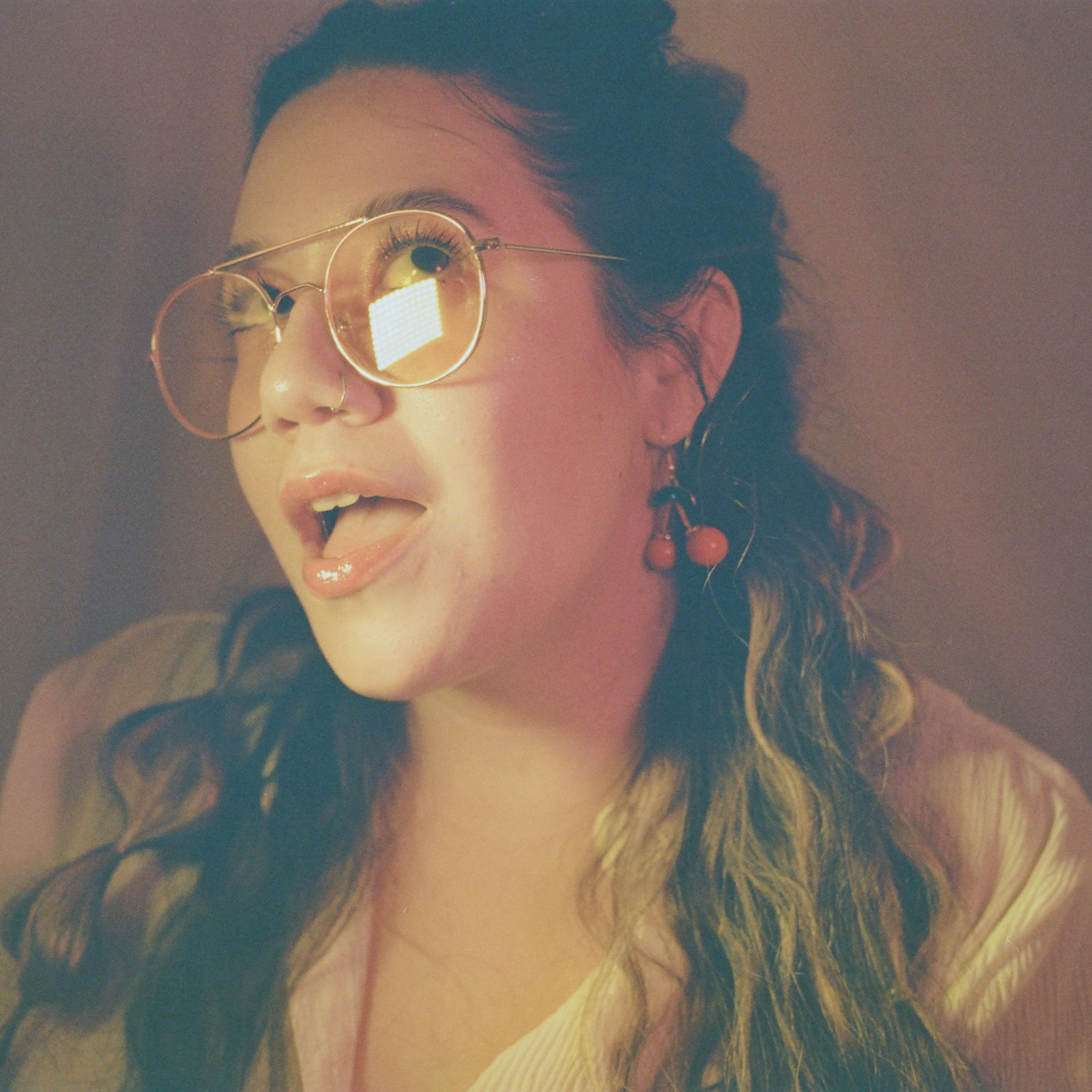 Portrait of woman with studio lighting and cherry earrings on film by Natalie Carrasco